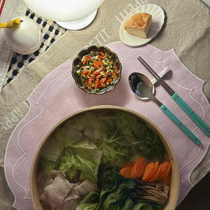 A beige and natural color dining space featuring a pink placemat, natural tableware, turquoise cutlery with a warm and cozy atmosphere