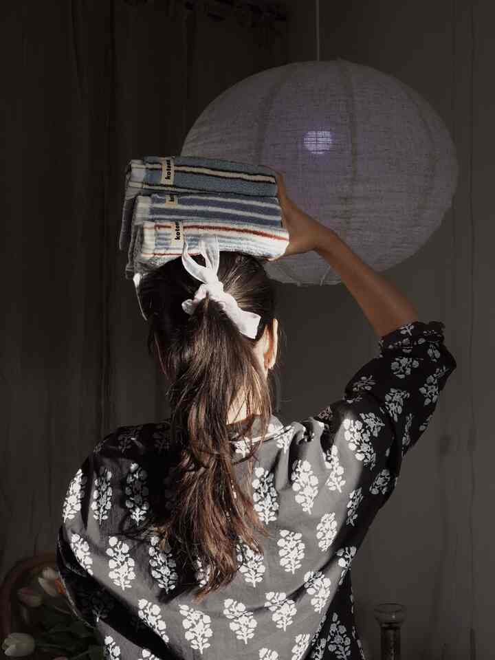 Bathroom space illuminated by natural light, featuring Kotona towels and a linen pendant light creating a natural atmosphere