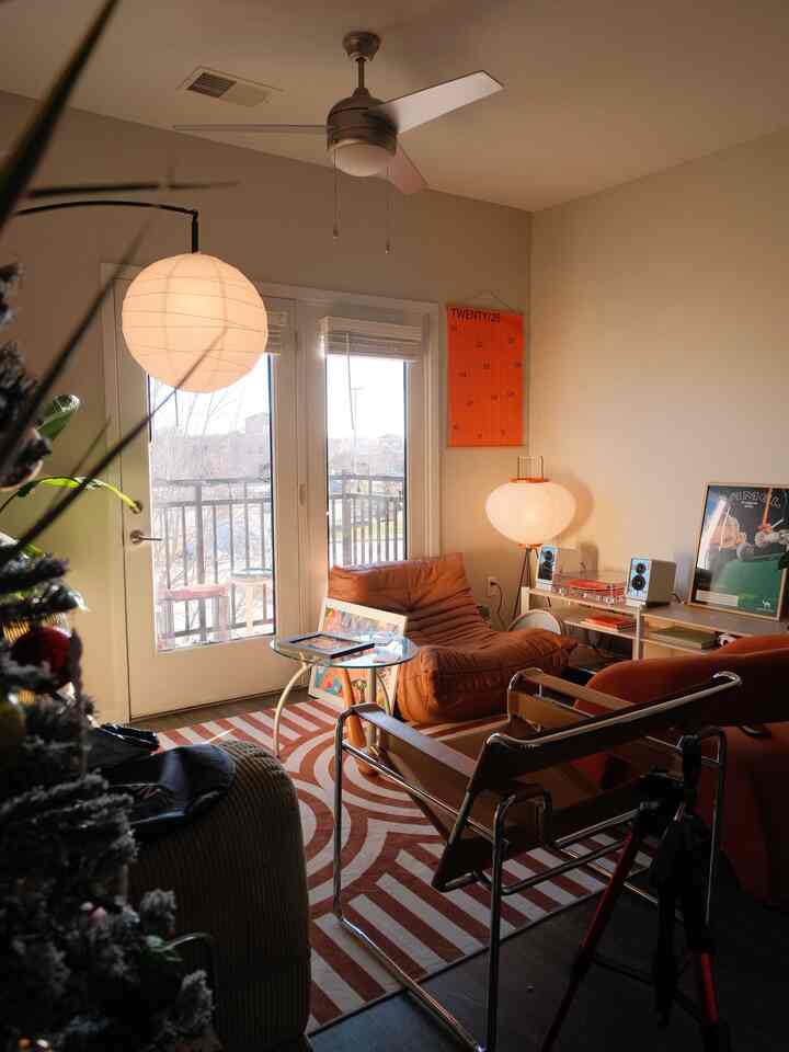 Warm red and brown toned living room featuring curvy striped rug and modern chairs with cozy ambiance