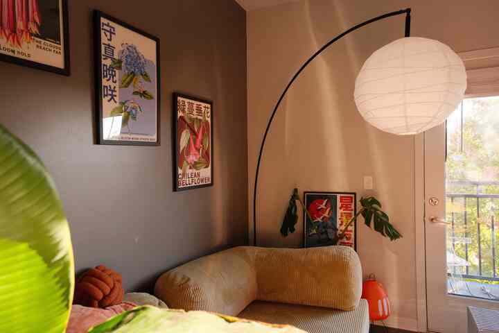 Natural color living room featuring corner sofa, floor lamp, and framed art on walls in a cozy atmosphere