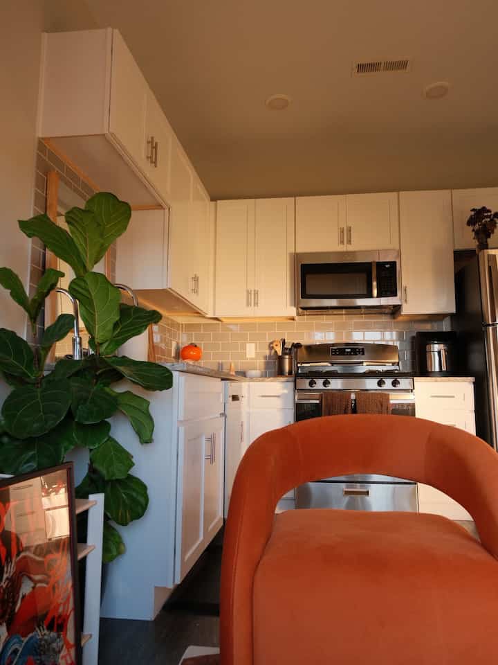 Warm orange armchair in a well-lit white kitchen space featuring modern cabinetry and appliances