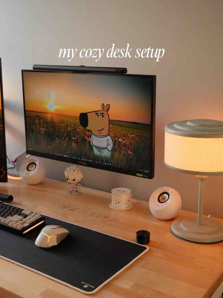 Wood tone desk with table lamp in a home office setup featuring computer monitor and peripherals creating a cozy atmosphere