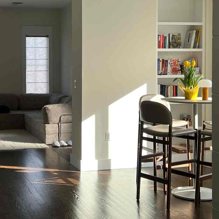 Beige and brown toned living and dining room featuring a beige sofa and a round dining table with yellow tulips, creating a cozy atmosphere
