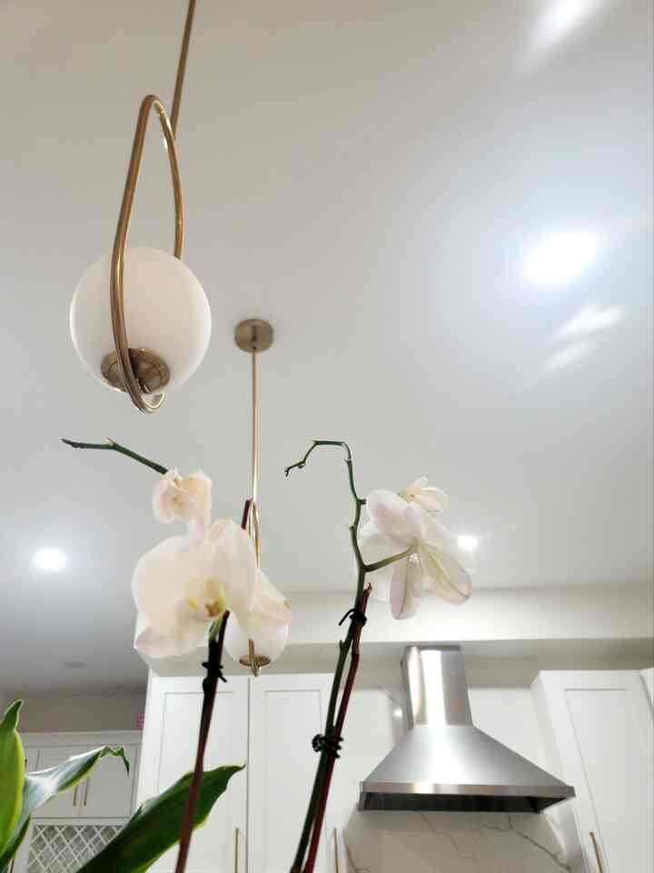 White and gold toned kitchen featuring pendant lights and range hood with a clean modern interior