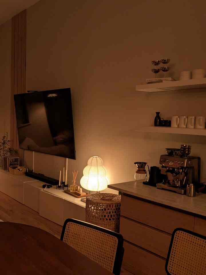 Warmly lit natural tone living room and kitchen space featuring a coffee machine and Noguchi Paper Lamp creating a cozy atmosphere