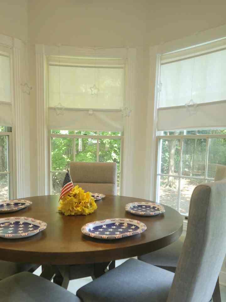 Dining room in white and brown tones featuring a round dining table and four chairs with natural light creating a cozy atmosphere