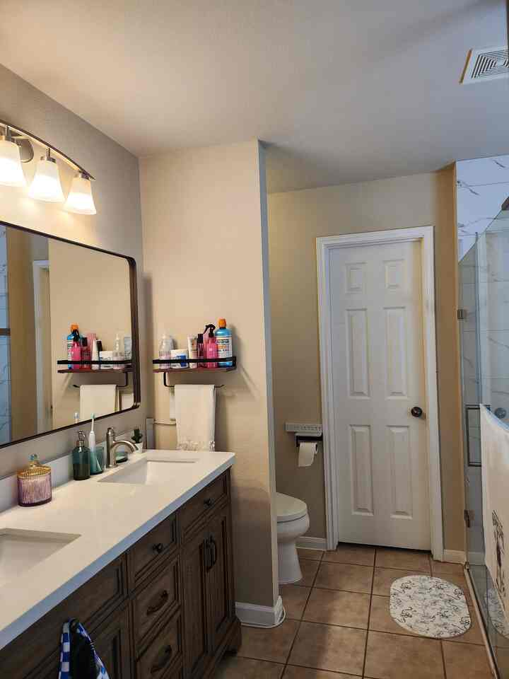 Beige-toned bathroom featuring wood tone vanity and tiled floor with a clean, cozy atmosphere