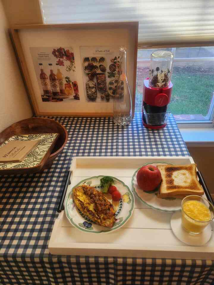 A blue checkered tablecloth with a white tray holding plates, food, and drinks arranged neatly in a kitchen dining area