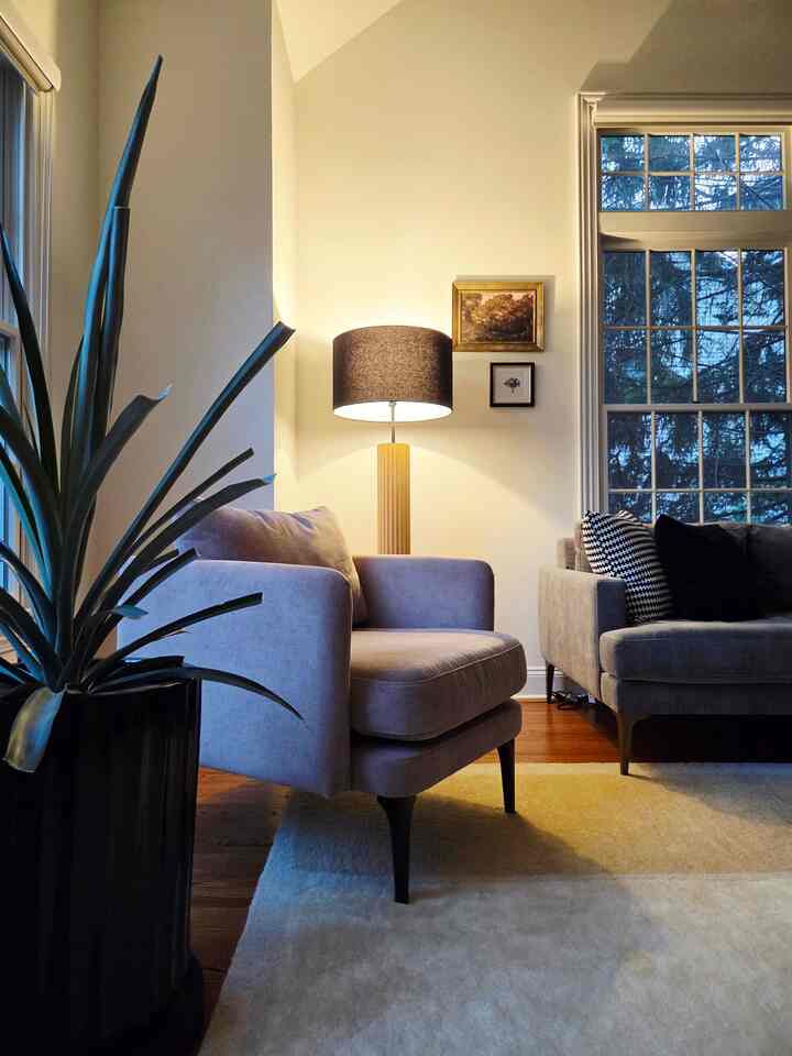 Light gray toned living room featuring a beige armchair and golden floor lamp creating a natural ambiance