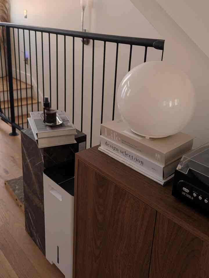 Natural wood tone and white living room cabinet with a round white lamp and Bluetooth record player, creating a cozy atmosphere