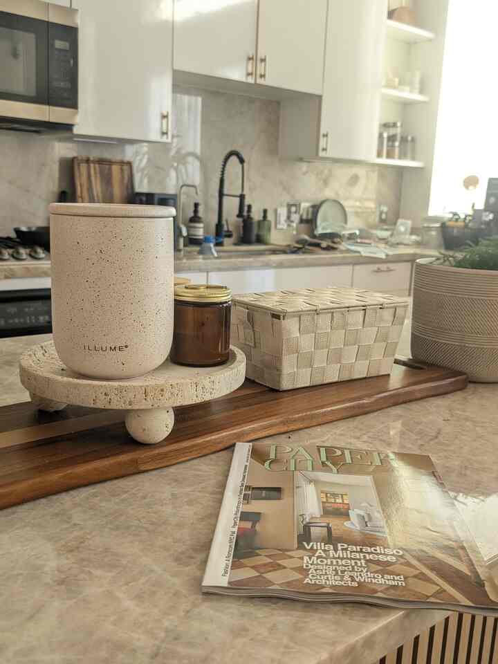 Natural color kitchen island featuring candles, a magazine, and a plant creating a cozy home cafe atmosphere