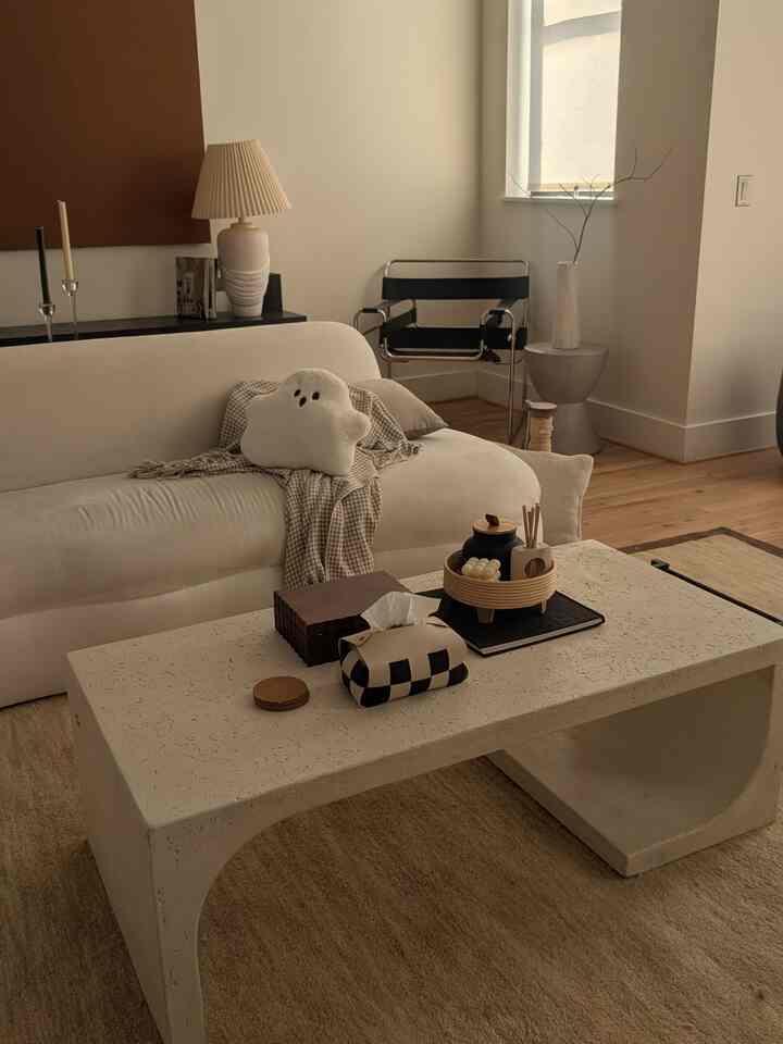 Natural modern toned living room featuring a white sofa, modern Wassily chair, and cement coffee table creating a cozy atmosphere