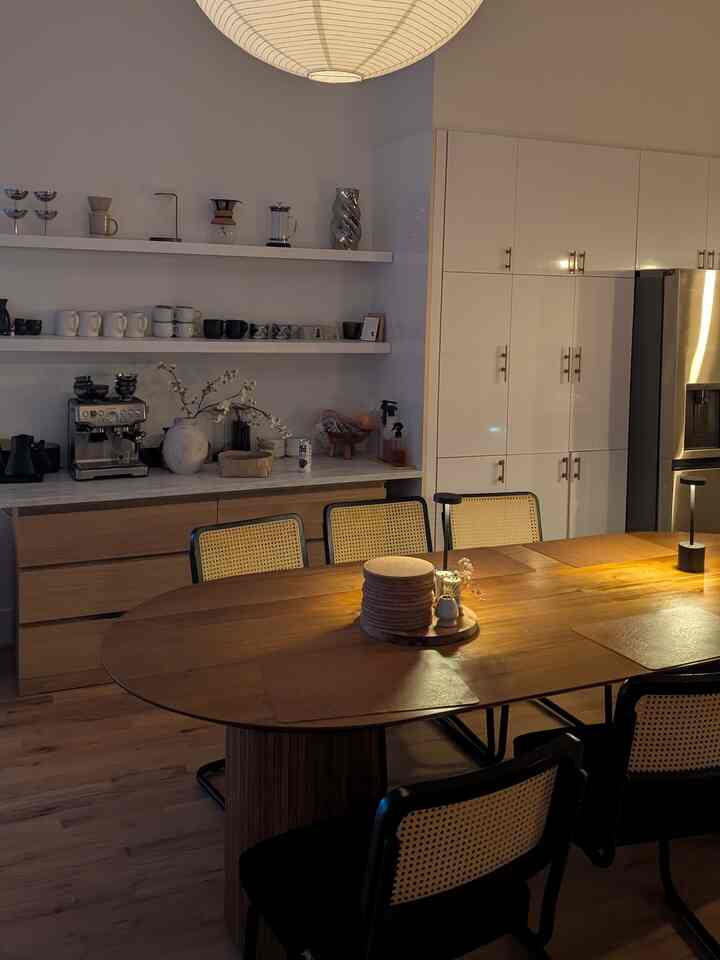 Warm wood tones and white kitchen featuring cafe-style dining table and chairs in a cozy space
