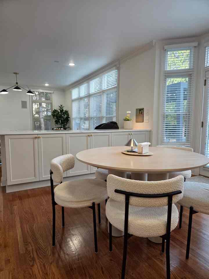 Bright white and brown toned kitchen and dining area featuring a round dining table and chairs with natural modern style in cozy atmosphere