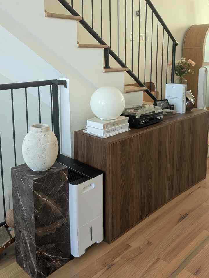 Wood tone under-stair living room space featuring a wooden cabinet and spherical table lamp creating a cozy atmosphere