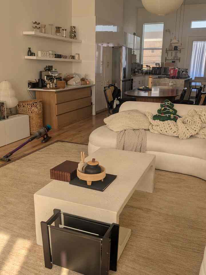 Natural-toned living and kitchen space featuring beige sofa and white coffee table with a cozy atmosphere