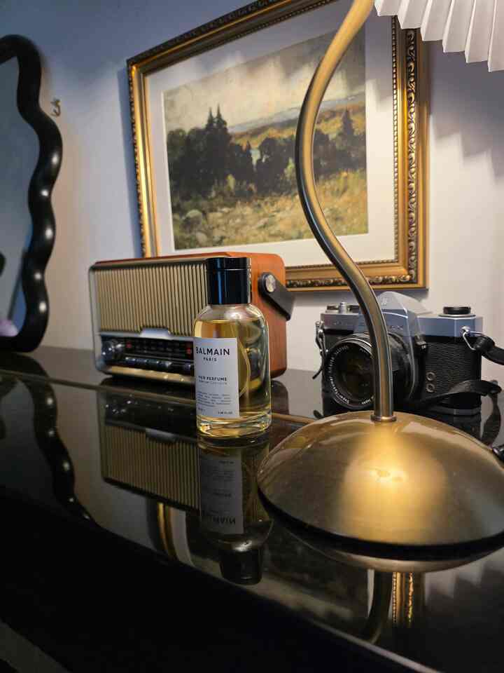 Vintage style desk featuring gold-tone table lamp, vintage camera, radio, and perfume bottle with warm atmosphere