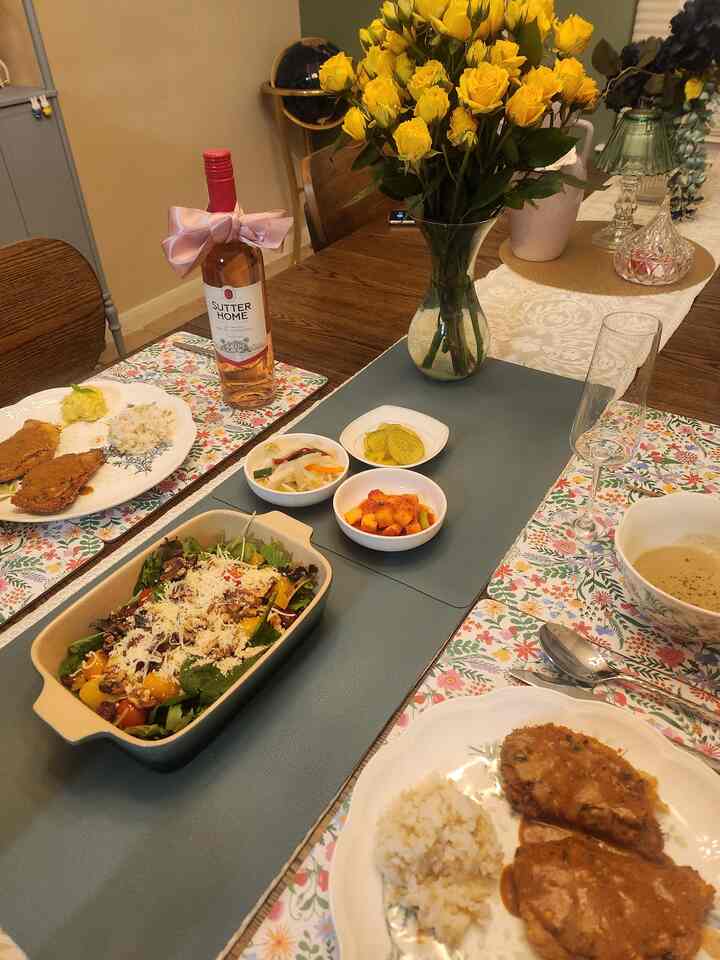 Beige-toned dining room with wood tone table, yellow rose centerpiece, and neatly set table indicating a cozy home party