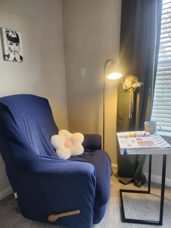 Quiet reading nook with navy recliner, beige walls, and warm light from a floor lamp