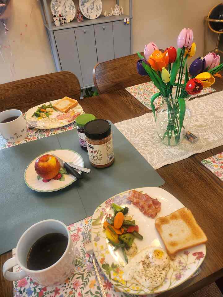 Brown-toned dining room featuring wooden dining table and chairs with a vase and breakfast setting in a cozy atmosphere