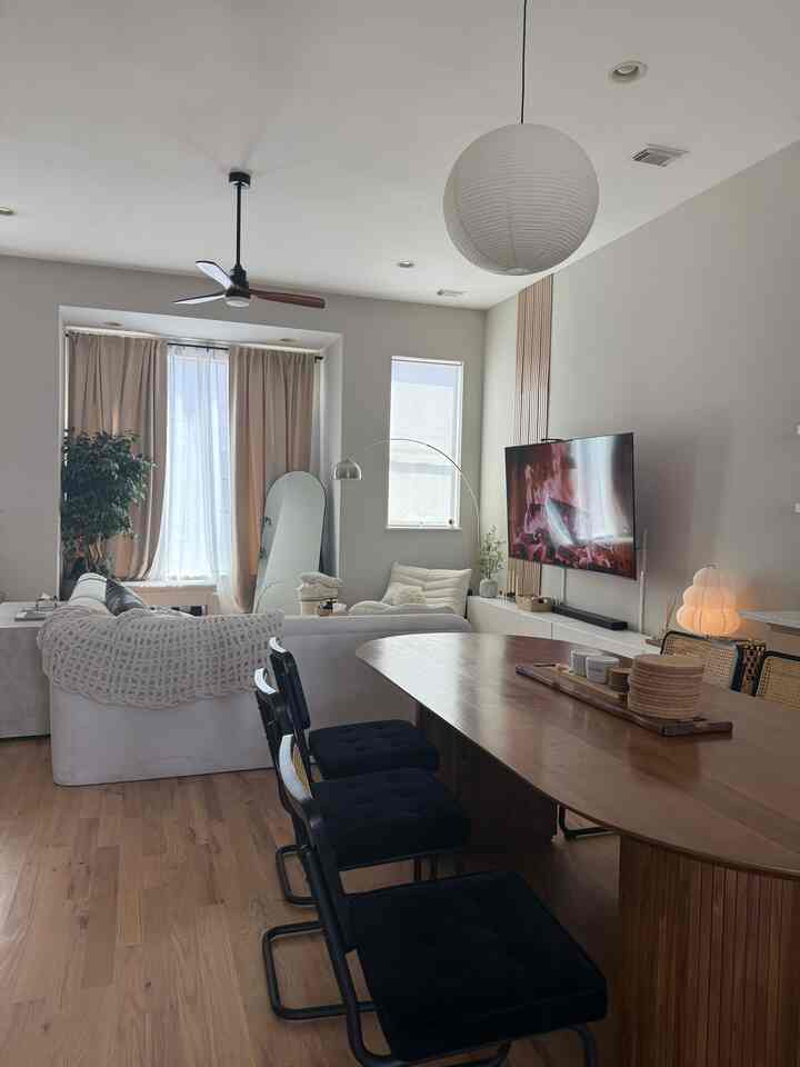 White and brown toned living and dining room featuring Mid-Century Modern wooden dining table and sofa in a clean space