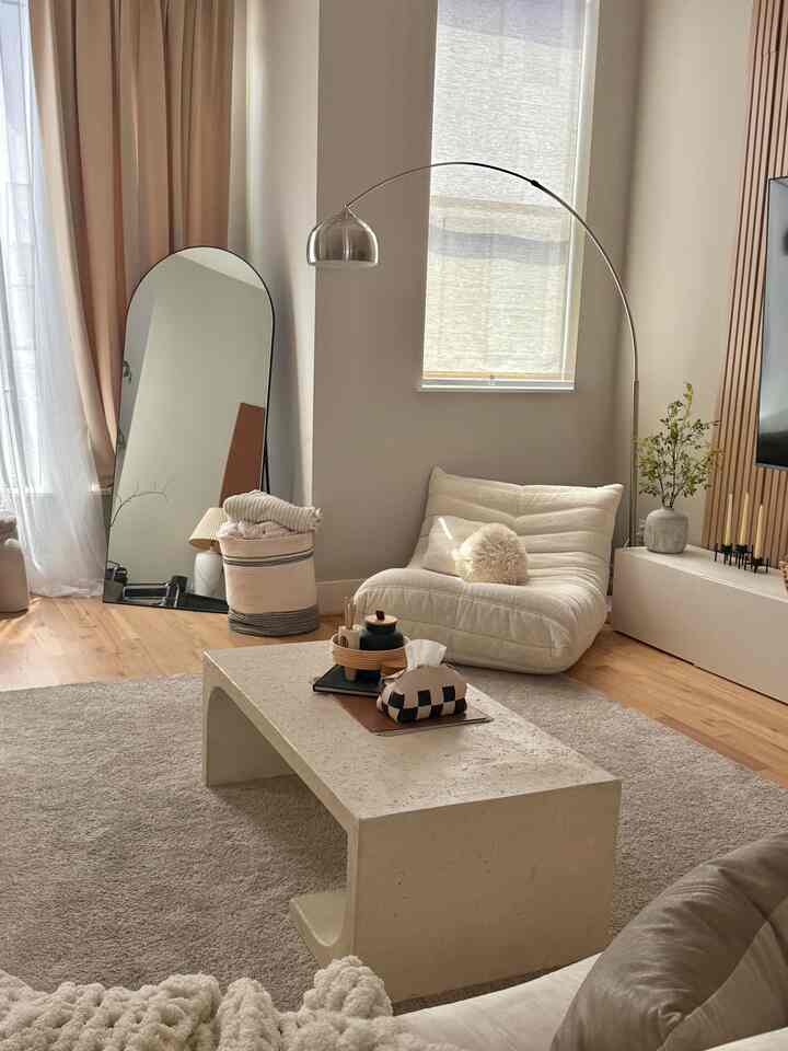 Beige and wood tone living room featuring a minimal sofa and arched floor lamp with a warm and cozy atmosphere