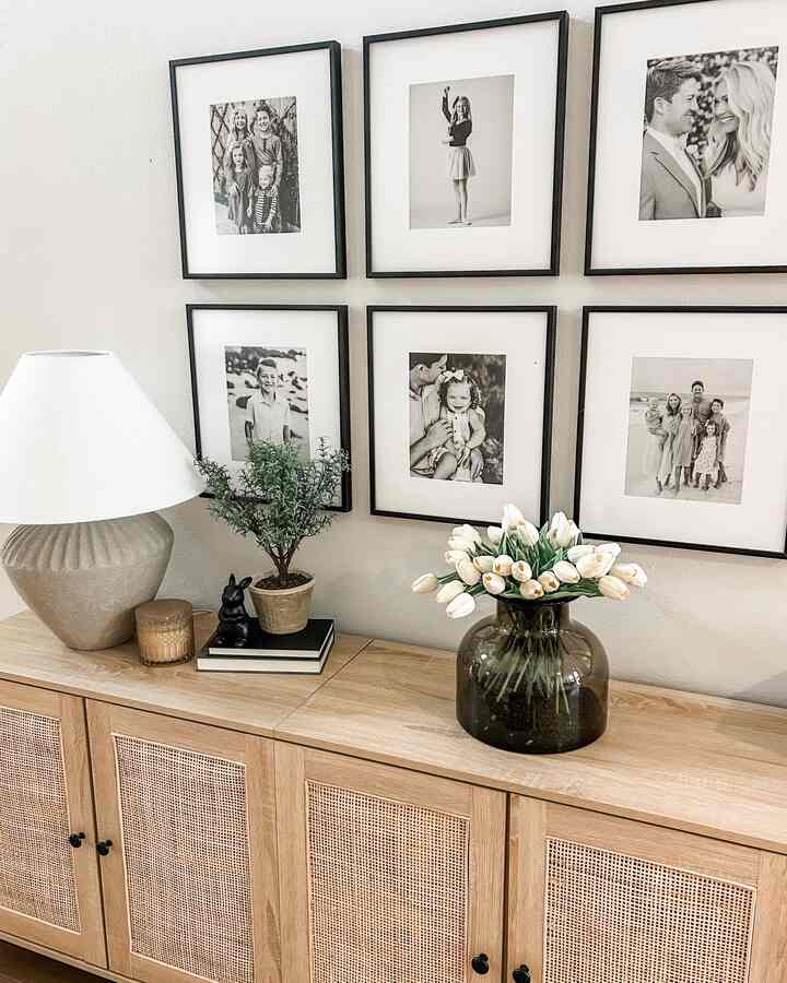 Natural toned entrance area featuring a rattan cabinet topped with a tulip vase and black picture frames in a cozy ambiance