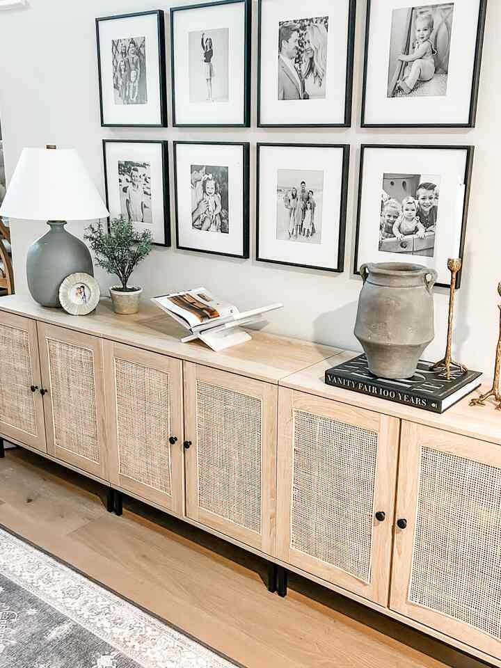 Natural entrance area with light wood tone cabinet and black picture frames on beige wall
