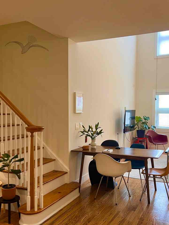 Natural Nordic dining room with white walls, brown wood tones on table and stairs, featuring a clean modern layout