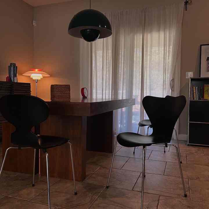 A natural wood-tone and black dining room featuring curtains and a pendant lamp, creating a cozy atmosphere
