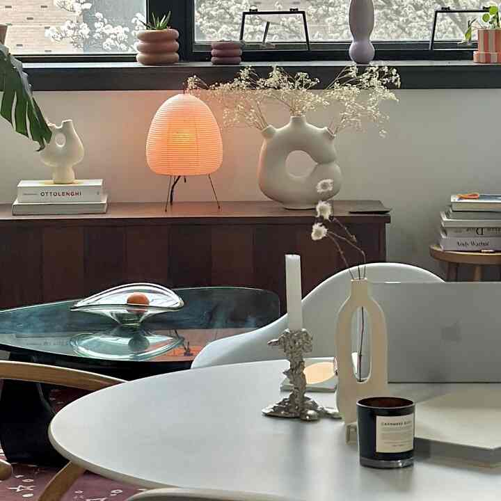 Cozy cafe-style living room with warm lighting and natural brown tones, featuring a smooth curved table and decorative objects