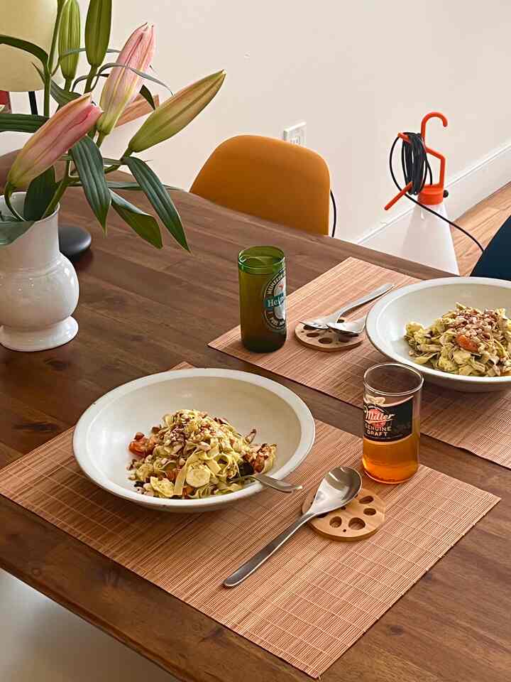 Natural wood-tone dining room with vase of flowers, arranged cutlery set, and lunch setting creating a warm feeling