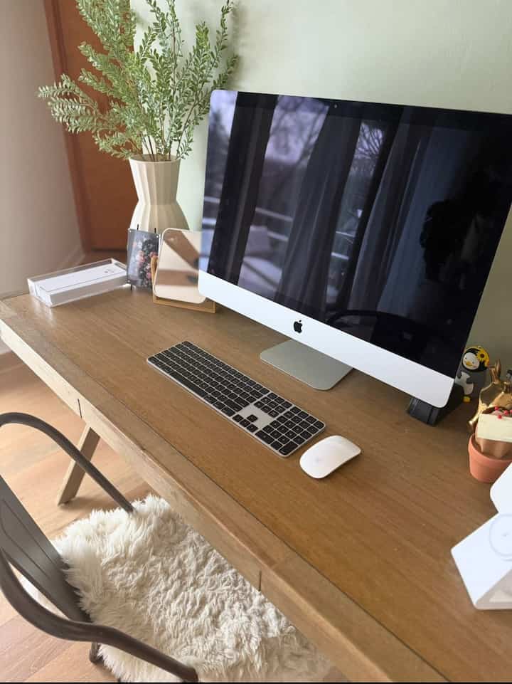 Warm brown wood-tone home office space featuring a wooden desk with iMac and leafy plant creating a natural mood