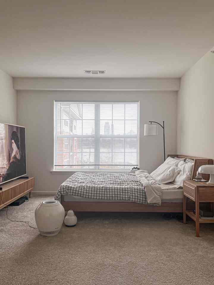 White and beige toned bedroom featuring natural wood bed and TV stand with a calm atmosphere