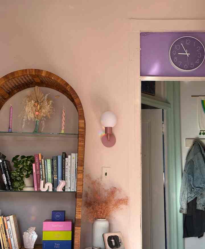 Natural toned living room featuring a rattan bookshelf and a wall sconce creating a cozy atmosphere