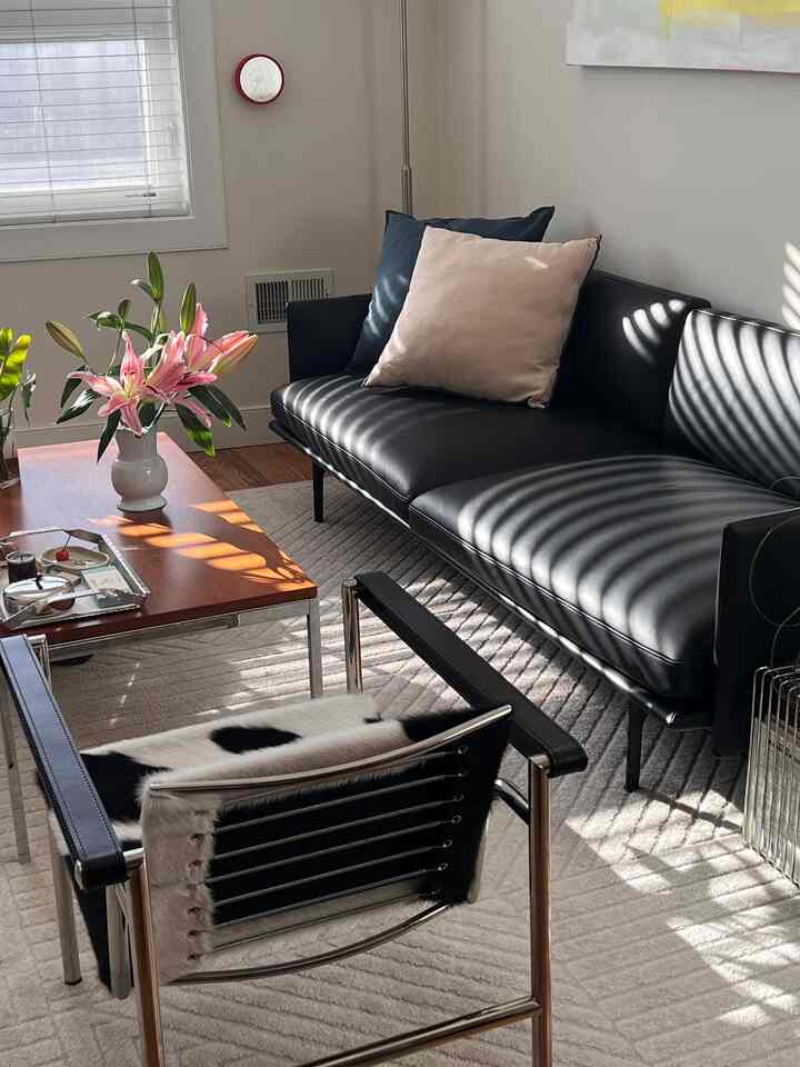 Living room with black and brown tones featuring leather sofa and armchair, wooden coffee table creating cozy atmosphere