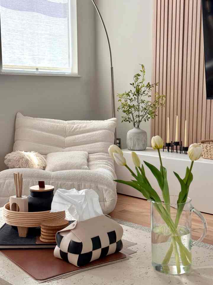 Beige and white tone living room with boucle armchair and white tulip bouquet, featuring a soft, natural, and cozy atmosphere