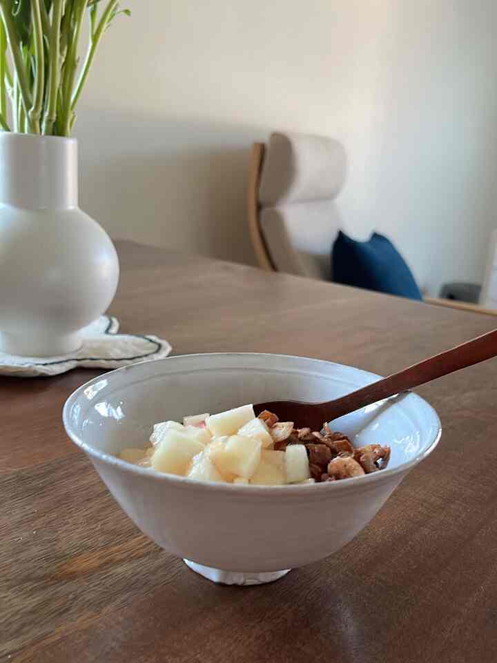 Natural modern dining room with white walls and wood tone dining table, featuring a white bowl and beige dining chair