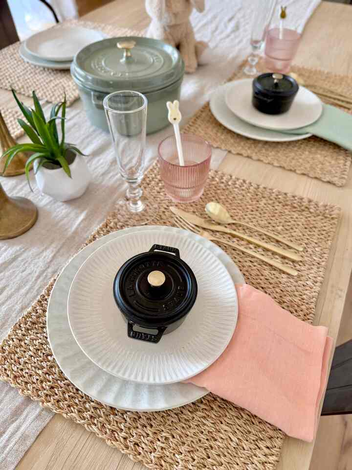 Pastel and natural color toned dining room featuring woven placemats and white tableware on a natural wood table creating a cozy ambience