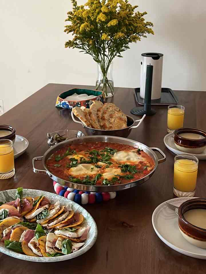 A cozy dining room with yellow flowers and wood tone table, featuring brunch plates and drinks for a warm home party setting