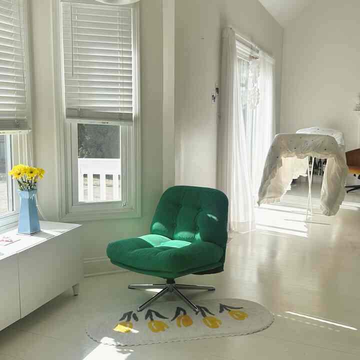 Bright white balcony space featuring a green armchair with sunlight creating a cozy atmosphere