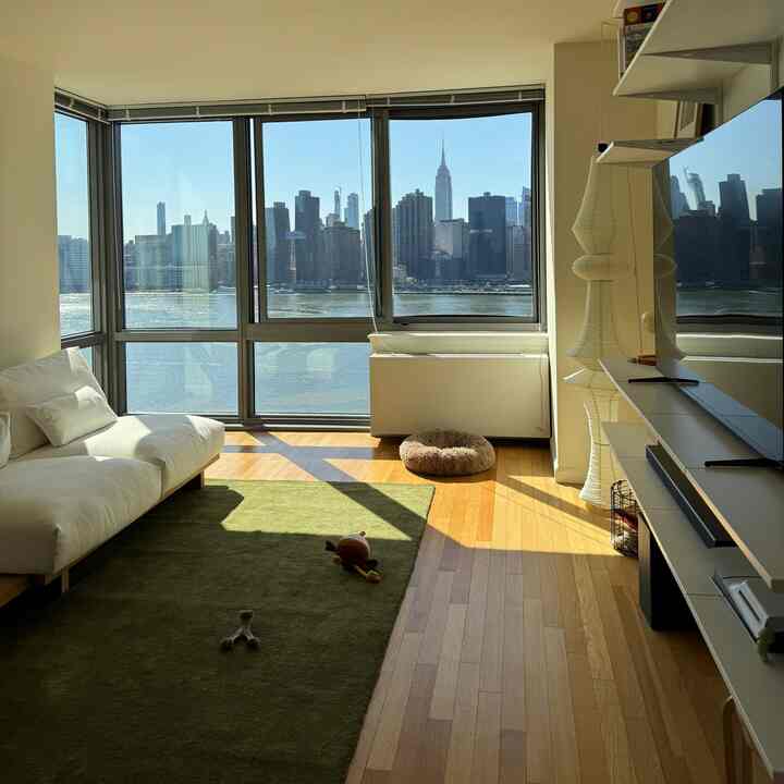 Bright living room with white sofa and wood tone floor, featuring pet bed and wall-mounted desk in natural modern style