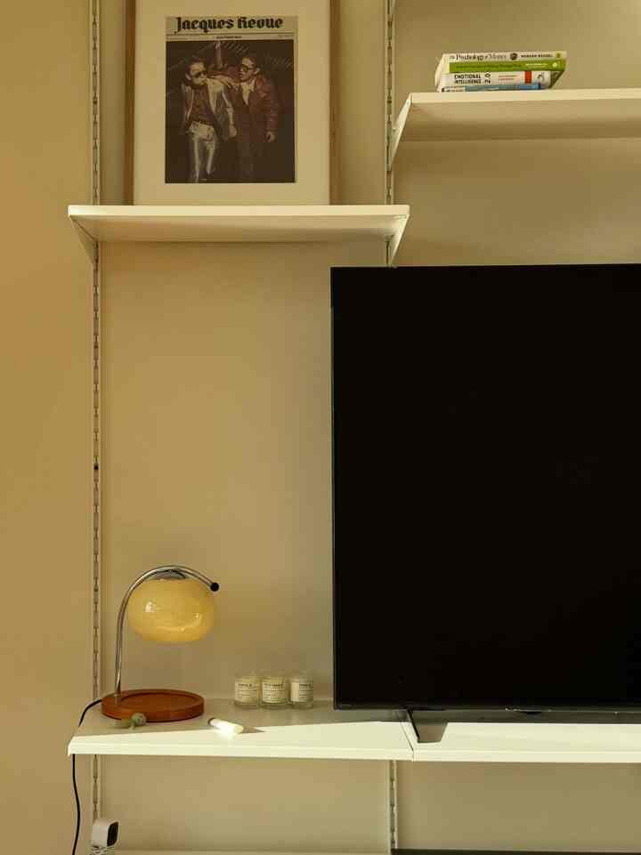Warm beige-toned wall with central white shelves in a modern style space featuring a yellow glass table lamp and candles creating a cozy atmosphere