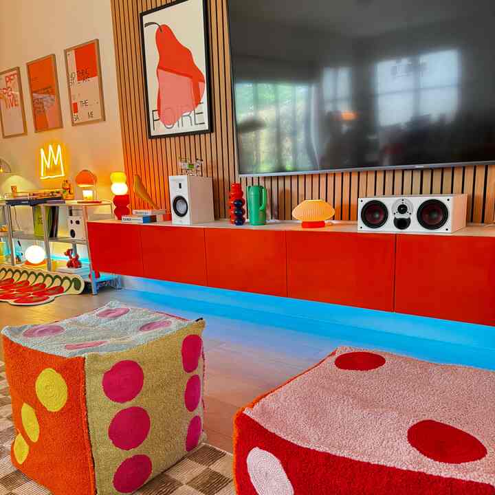 Orange-toned living room featuring a retro media console with colorful patterned cushions creating a cozy atmosphere