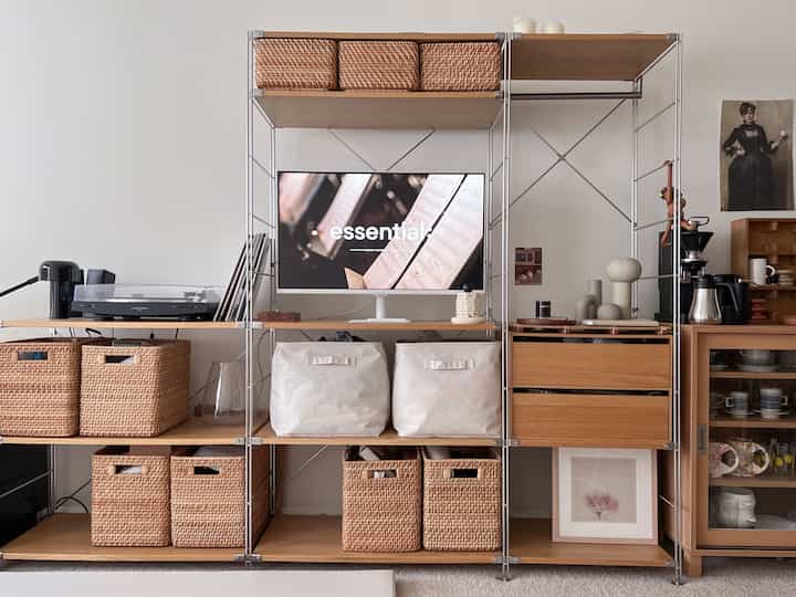 Natural wood tone living room featuring central shelving and TV stand with a minimal and cozy atmosphere