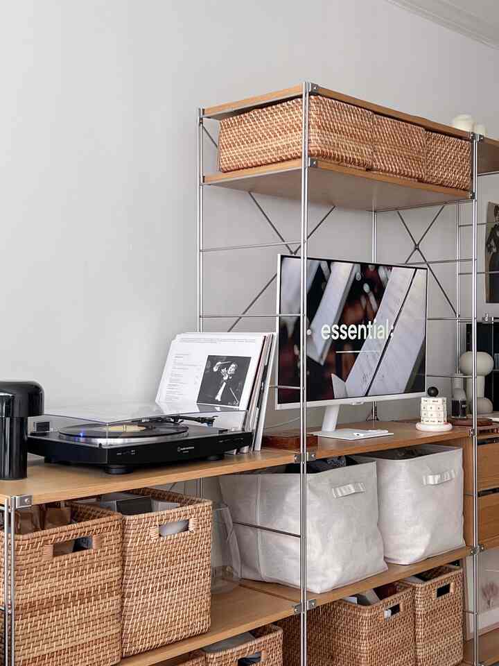 Natural and wood-tone shelving in a living room space featuring black electronics and baskets creating a calm atmosphere