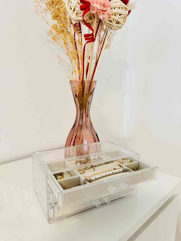 Clean space with white background and transparent acrylic organizer, pink vase with dried flowers