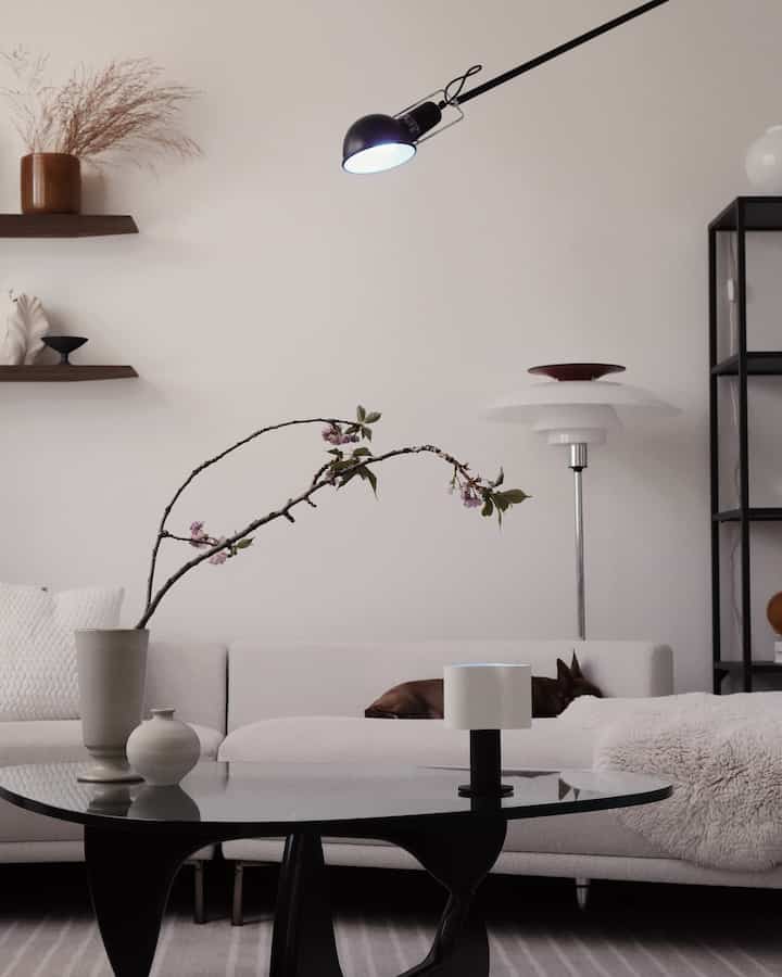 White and black toned living room featuring a sofa and coffee table at center, with a vase of spring flowers, creating a cozy atmosphere