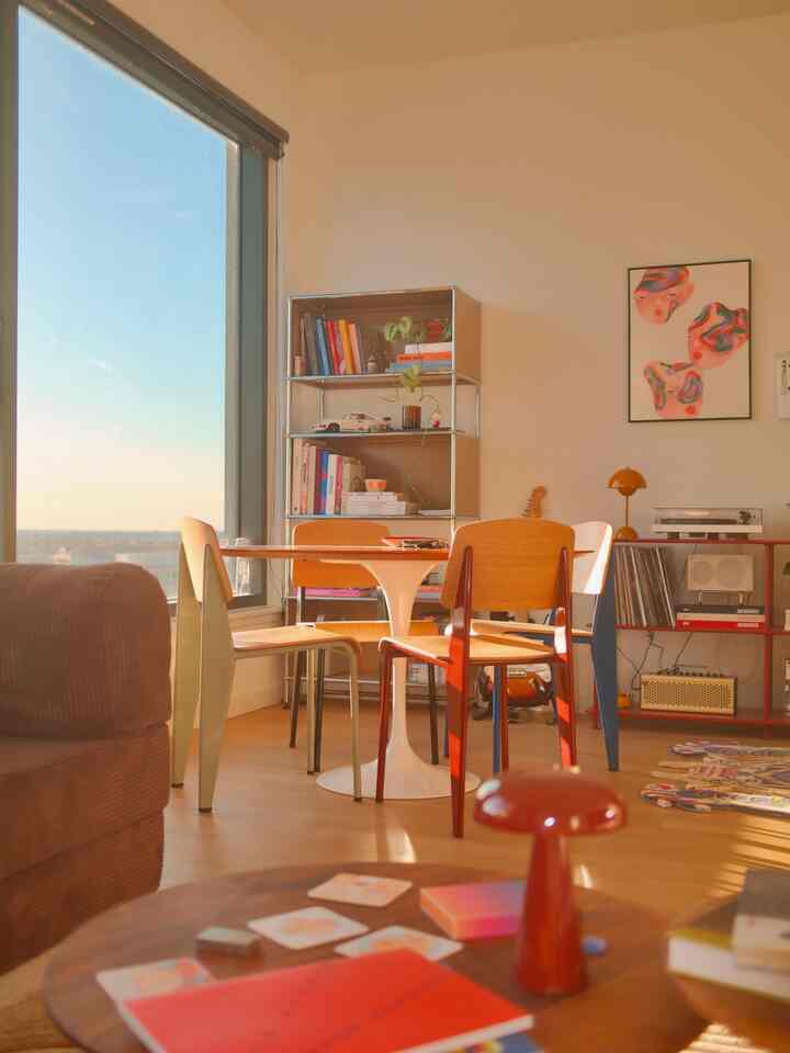 Warm natural tones living and dining room with wooden chairs, white dining table, and cozy atmosphere illuminated by natural daylight