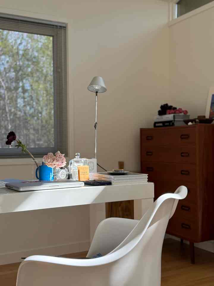Bright white and brown toned home office featuring mid-century modern furniture and a tidy desk with cozy atmosphere